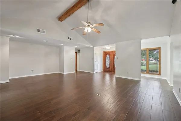 a view of an empty room with window and wooden floor