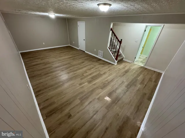 a view of an empty room with wooden floor and stairs