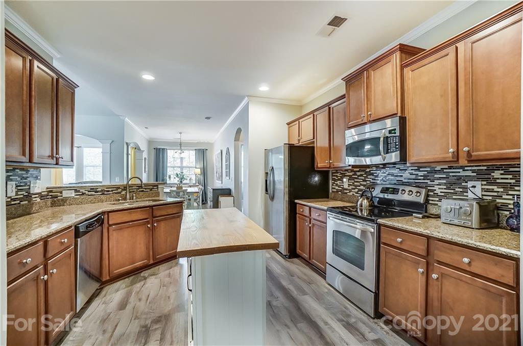 827 Solandra Way Fort Mill, SC 29708 - Photo 20 of 43 a large kitchen with stainless steel appliances granite countertop a stove top oven a sink dishwasher a dining table and chairs with wooden floor