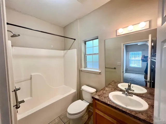 a bathroom with a granite countertop sink toilet a mirror and shower
