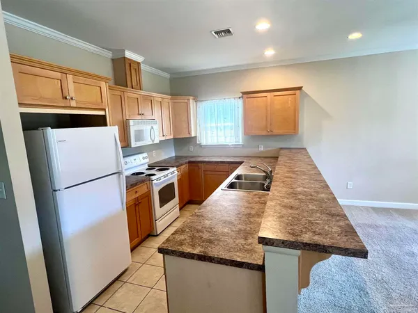 a kitchen with granite countertop a refrigerator a stove a sink and white cabinets