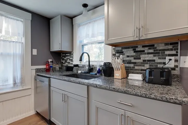 a kitchen with granite countertop a sink a stove and cabinets
