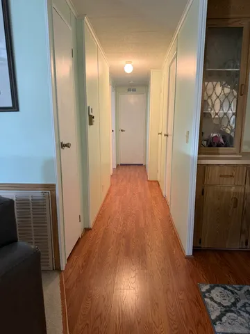 a view of a hallway with wooden floor and a bathroom