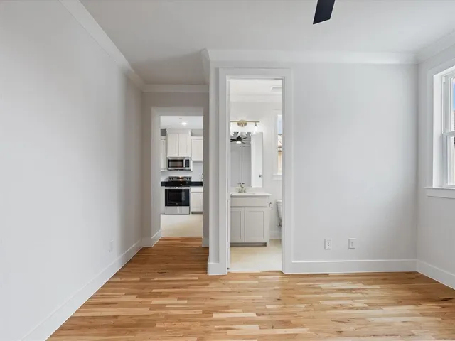 a view of a hallway with wooden floor and a kitchen