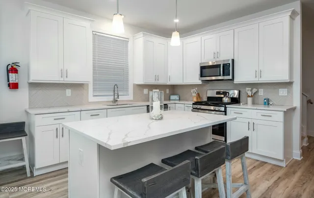 a kitchen with stainless steel appliances a sink a stove a refrigerator cabinets and a window