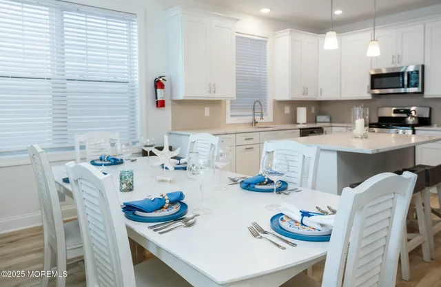 a kitchen with stainless steel appliances kitchen island granite countertop a sink a stove a dining table and chairs
