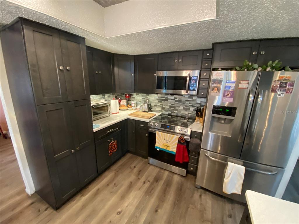 4100 Montano Avenue Spring Hill, FL 34609 - Photo 11 of 59 a kitchen with a refrigerator sink and wooden floor