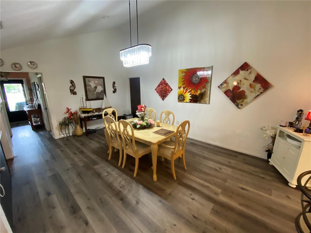 4100 Montano Avenue Spring Hill, FL 34609 - Photo 19 of 59 a view of a dining room with furniture wooden floor and a chandelier