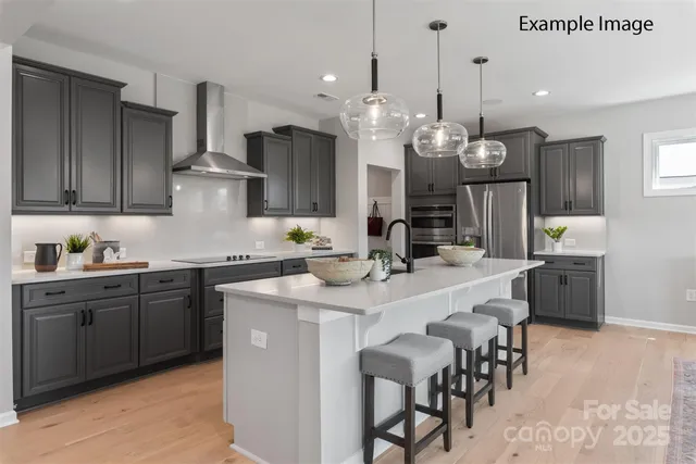 a kitchen with stainless steel appliances kitchen island granite countertop a sink a stove a refrigerator and island with wooden floor