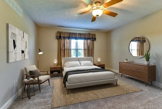 a bedroom with a bed a chandelier and a mirror on the dresser