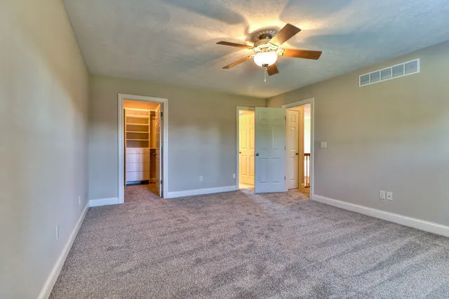 an empty room with closet and a ceiling fan