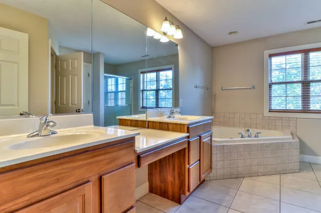 a spacious bathroom with a sink double vanity granite tub shower and a mirror