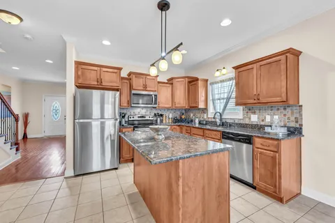 a kitchen with stainless steel appliances granite countertop a sink a stove a refrigerator and island with wooden floor