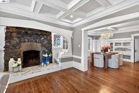 a living room with furniture a fireplace and a dining table with wooden floor