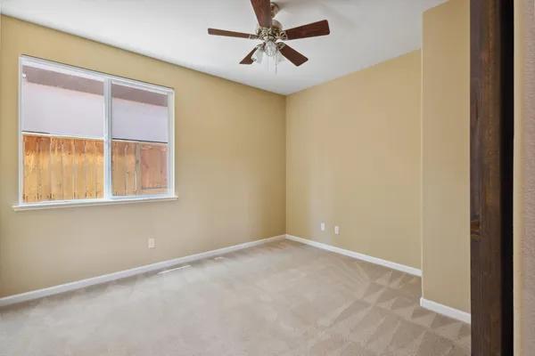 an empty room with a window and a fan