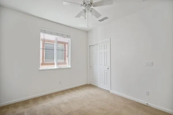 an empty room with a window and a ceiling fan