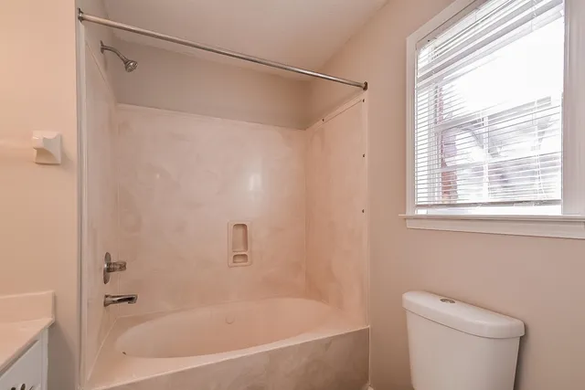 a bathroom with a granite countertop bathtub shower sink vanity and toilet