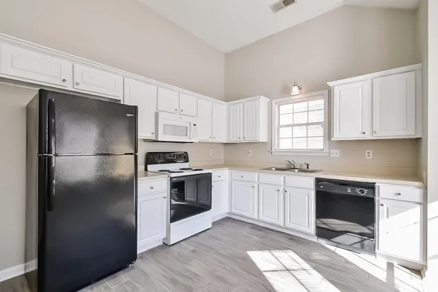 a view of an empty room with wooden floor fireplace and a window