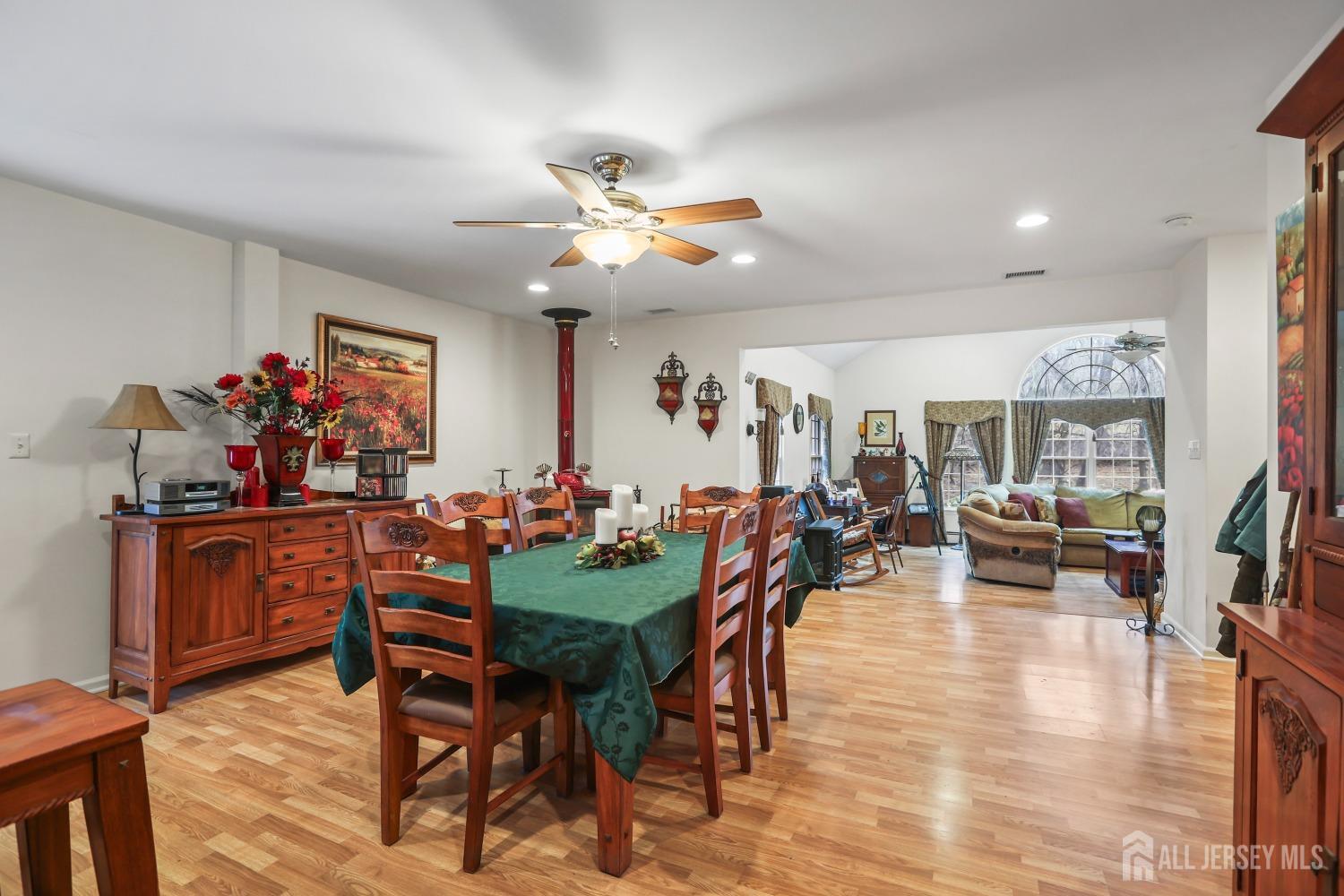 75 Baird Road Millstone Township, NJ 08535 - Photo 8 of 30 a view of a dining room and livingroom with furniture wooden floor a rug a flat screen tv a painting and a chandelier