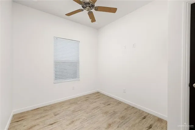 an empty room with a window and a fan