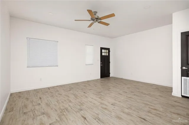 an empty room with wooden floor and ceiling fan