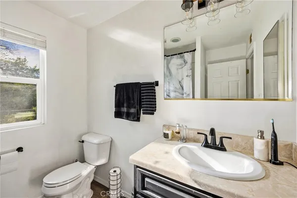 a bathroom with a granite countertop toilet sink and mirror