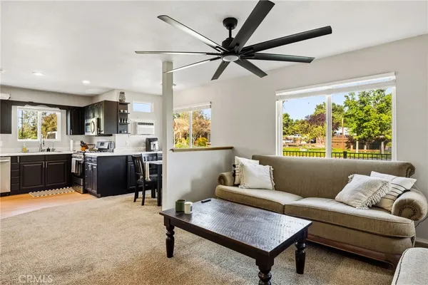 a living room with furniture kitchen area and a window