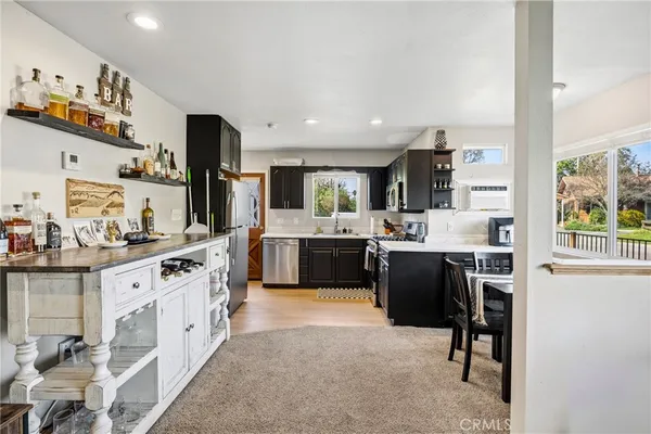 a kitchen with stainless steel appliances a sink a stove a refrigerator cabinets and a window