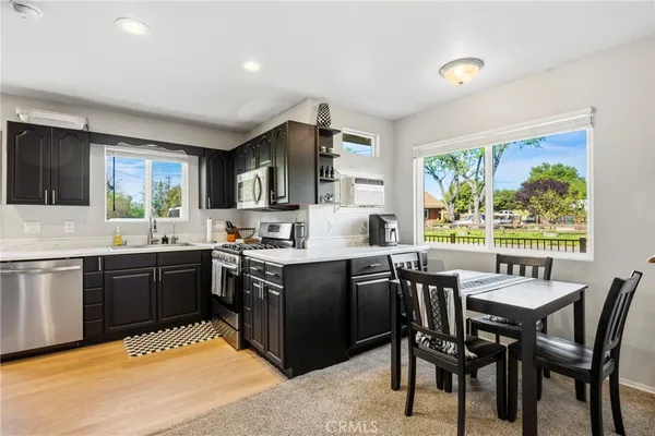 a kitchen with stainless steel appliances granite countertop table chairs sink and window