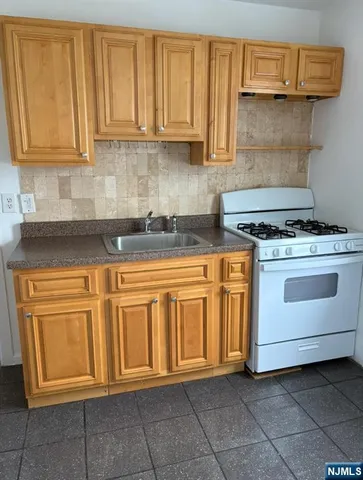 a kitchen with granite countertop a stove top oven microwave and cabinets