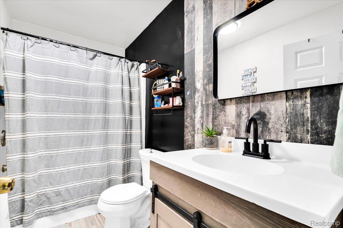 3260 Isabelle Street Inkster, MI 48141 - Photo 23 of 35 Bathroom featuring a wood-finish vanity with a white countertop and oval undermount sink, matte black faucet, and a large rectangular mirror