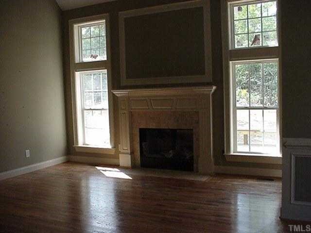 39 High Ridge Court Willow Spring, NC 27592 - Photo 2 of 8 an empty room with wooden floor fireplace and windows
