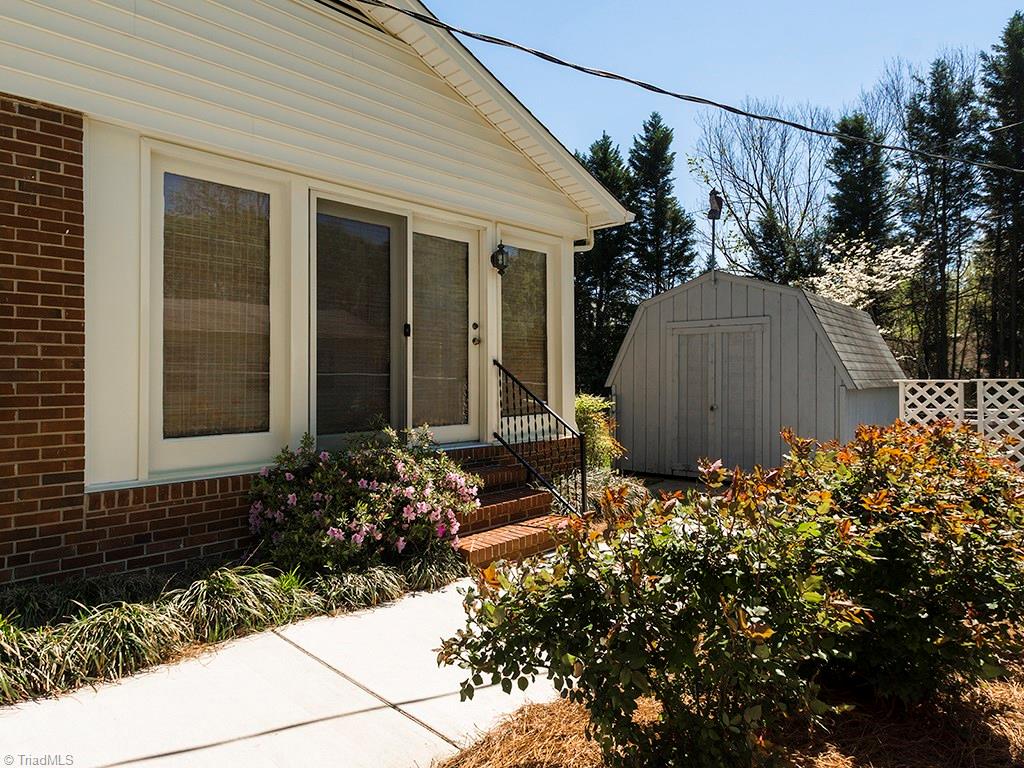4521 Tower Road Greensboro, NC 27410 - Photo 28 of 28 Right side of the house featuring side entrance into the sunroom and the storage building