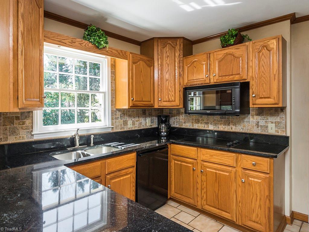 4521 Tower Road Greensboro, NC 27410 - Photo 9 of 28 The kitchen offers good workspace on granite counter tops with a tile back splash.