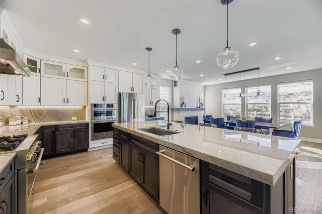 a kitchen with stainless steel appliances granite countertop a sink a stove and a wooden floors