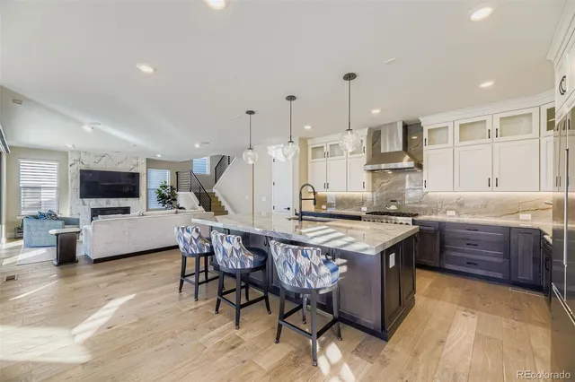 a kitchen with stainless steel appliances granite countertop a stove top oven a sink dishwasher a dining table and chairs with wooden floor