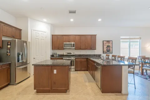 a kitchen with stainless steel appliances granite countertop a stove top oven a refrigerator a sink and dishwasher with wooden floor
