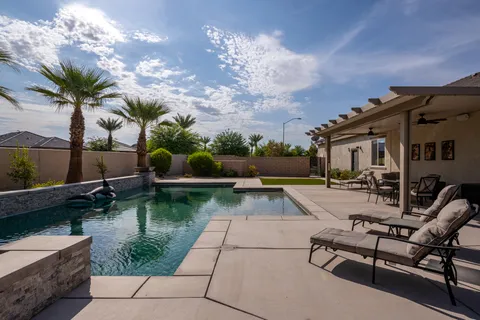 a view of a swimming pool with a patio and a yard