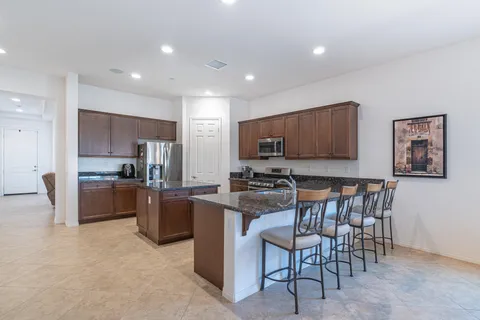 a kitchen with stainless steel appliances granite countertop a stove top oven a sink dishwasher a dining table and chairs with wooden floor