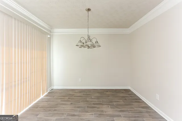 a view of a room with a chandelier fan and wooden floor