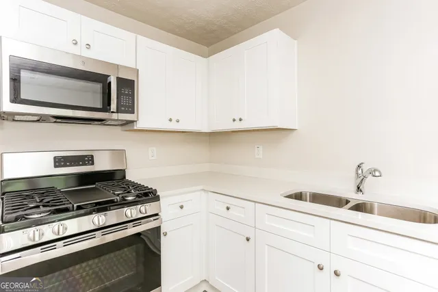a kitchen with white cabinets and appliances