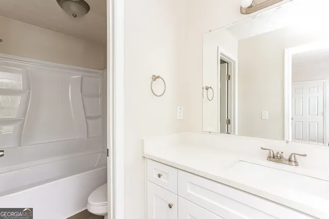 a bathroom with a granite countertop sink a toilet and bathtub
