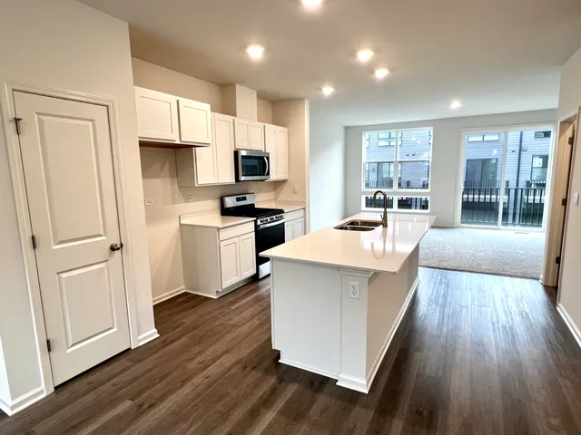 a white kitchen with wooden floor and stainless steel appliances