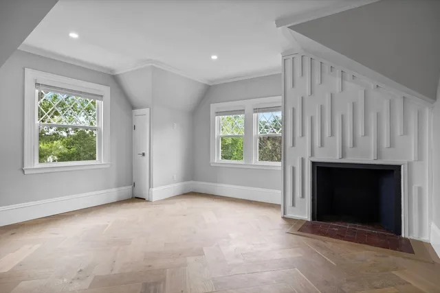 an empty room with windows and fireplace