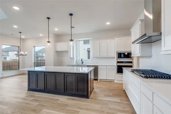 a large kitchen with stainless steel appliances granite countertop a stove a sink dishwasher and a refrigerator with wooden floor