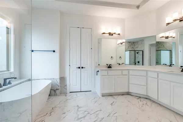 a spacious bathroom with a double vanity sink a mirror a bathtub and a shower