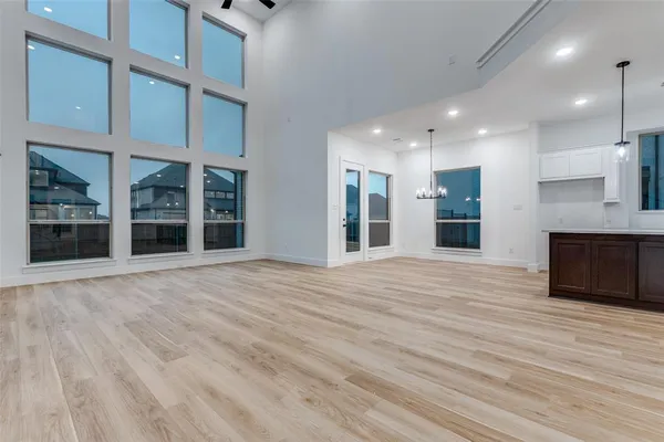 a view of an empty room with wooden floor and a kitchen