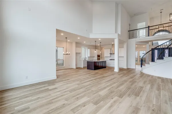 a view of empty room with wooden floor and a kitchen