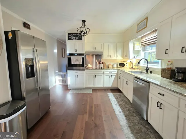 a large kitchen with stainless steel appliances kitchen island granite countertop a sink refrigerator and cabinets