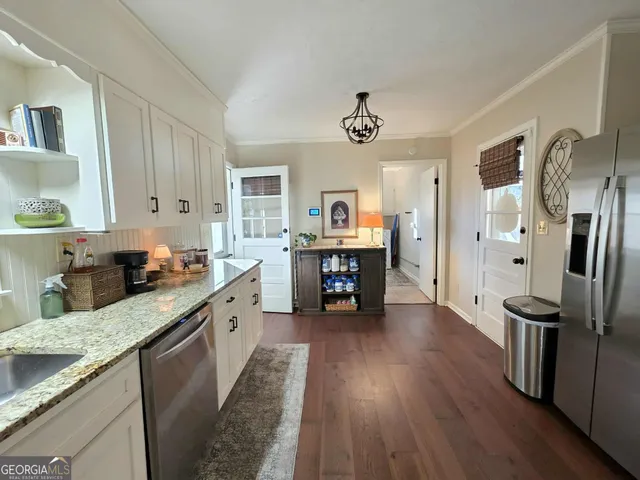 a large kitchen with stainless steel appliances granite countertop a lot of counter space and wooden floors